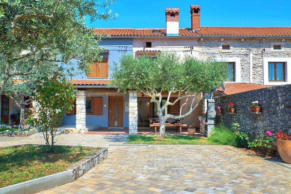 A stone building with a tiled roof, a central courtyard with a tree, and a stone wall with potted plants. - Holiday home Orihi * 2000 m2 fenced garden, covered terrace, BBQ (Barban)
