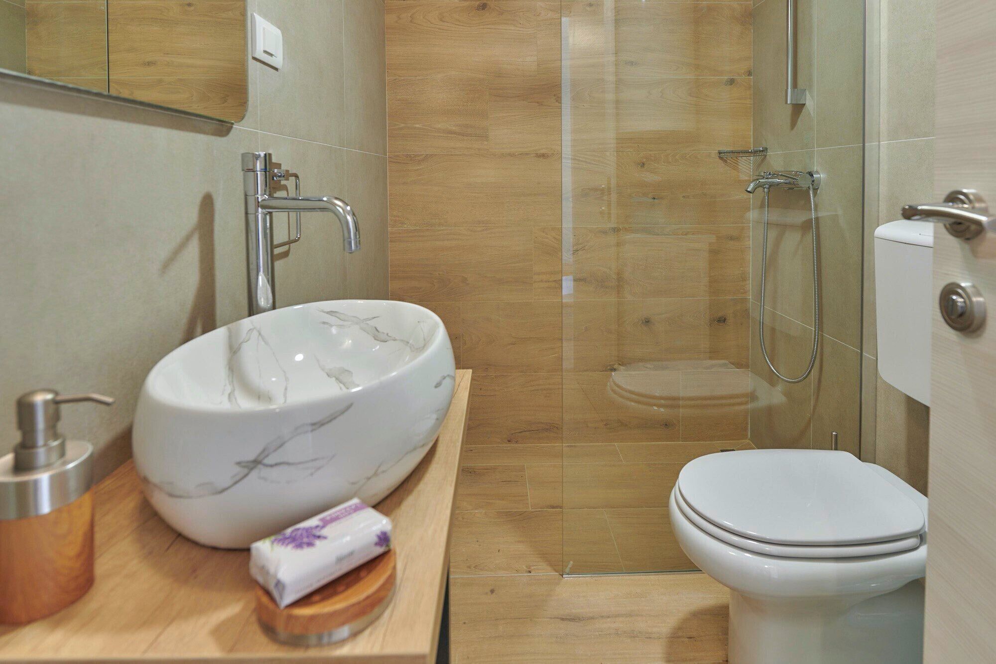 Une salle de bain moderne avec un grand lavabo en marbre blanc, des toilettes et une douche à parois de verre.