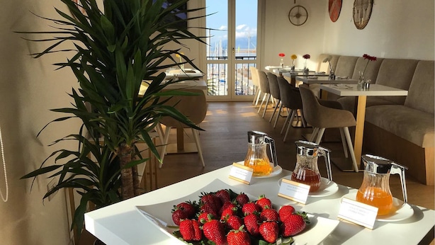 Una mesa blanca con un desayuno, una fuente de fresas y tres jarras de jugo.