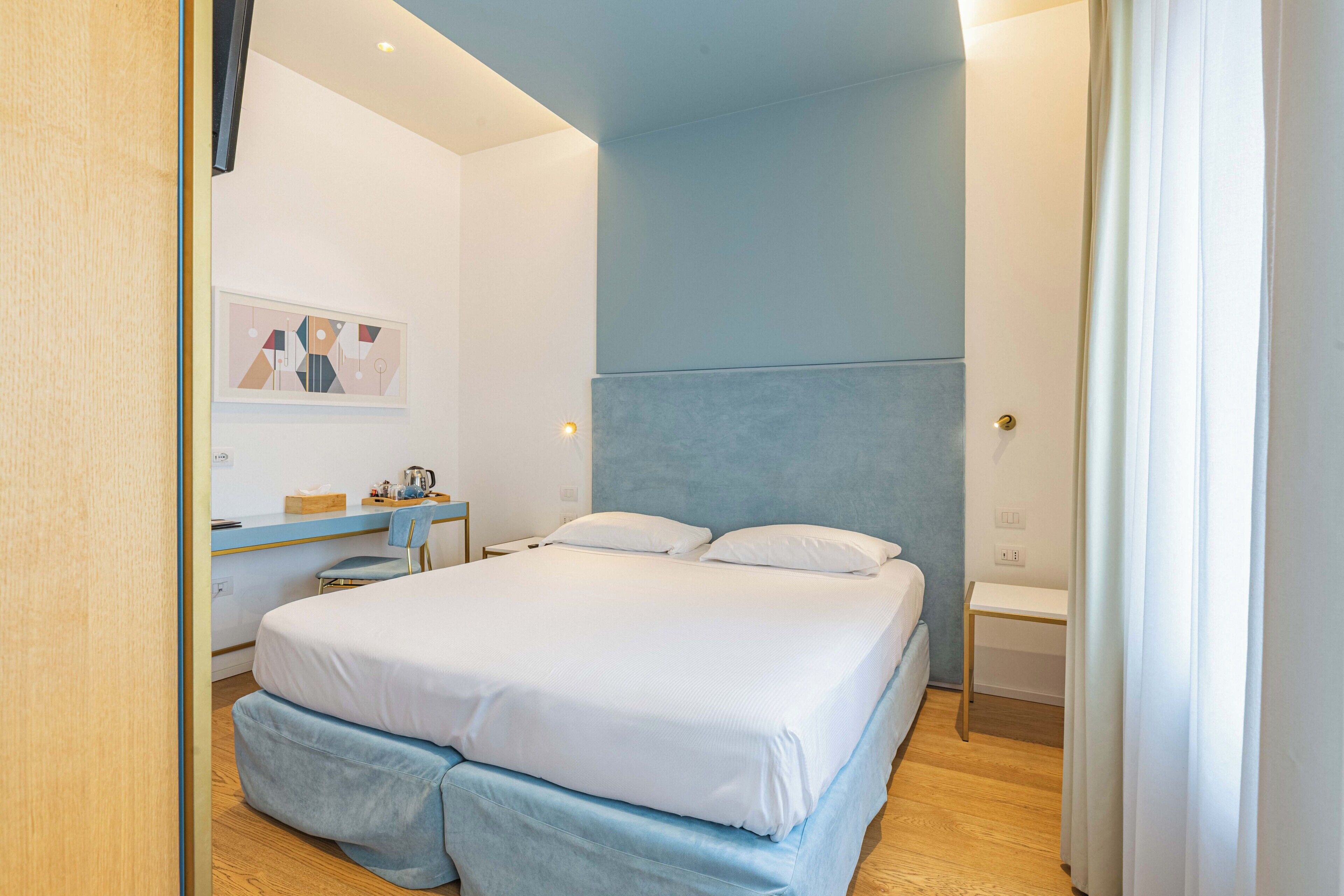 A modern bedroom with a large bed, a desk, and a chair.