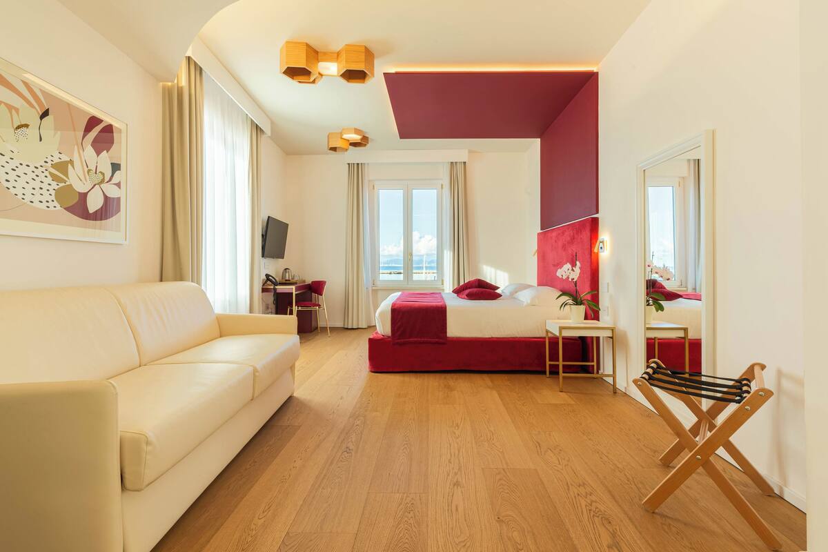 Moderni hotellihuone, jossa on suuri sänky, sohva, työpöytä ja televisio.