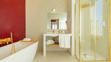 Un baño moderno con un tocador blanco, ducha con cerramiento de vidrio y una pared de acento roja.
