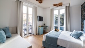 Una habitación de hotel con cama, escritorio, televisión y ventanas amplias.