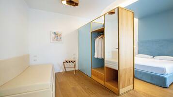 A modern bedroom with a bed, a wardrobe, and a small seating area.