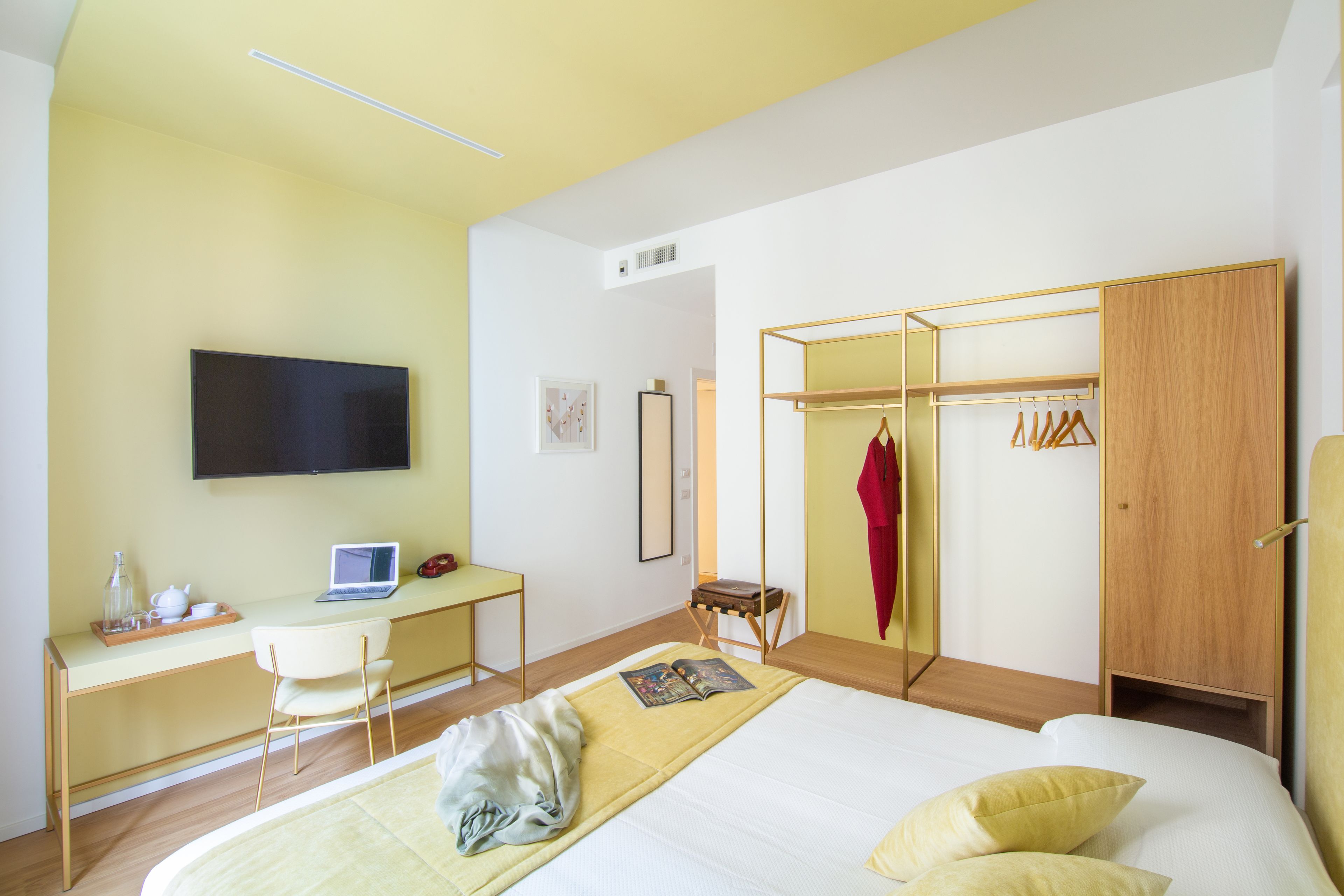 Un dormitorio moderno con cama, escritorio, silla, televisor y armario.