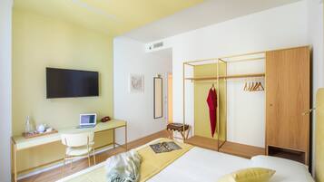 Un dormitorio moderno con cama, escritorio, silla, televisor y armario.