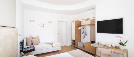 A modern bedroom with a bed, a desk, a wardrobe, and a TV.