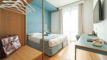 Ein Hotelzimmer mit einem Bett, einem Schreibtisch, einem Sessel, einem Fernseher und einem Koffer.