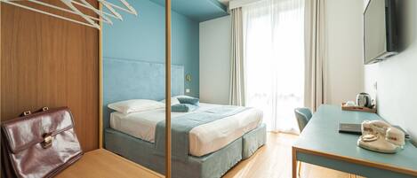 Una habitación de hotel con cama, escritorio, silla, televisión y maleta.