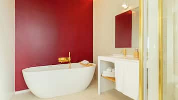 Ein modernes Badezimmer mit freistehender Badewanne, einem Waschtisch mit Spiegel und einer roten Akzentwand.