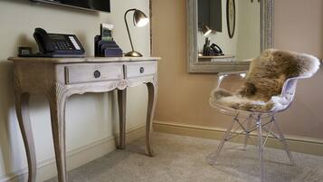 A room with a wooden desk, a telephone, a lamp, a mirror, and a fur chair.