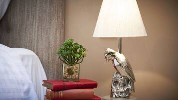 Ein Nachttisch mit Lampe, einer kleinen Pflanze und einer Vogelstatue.