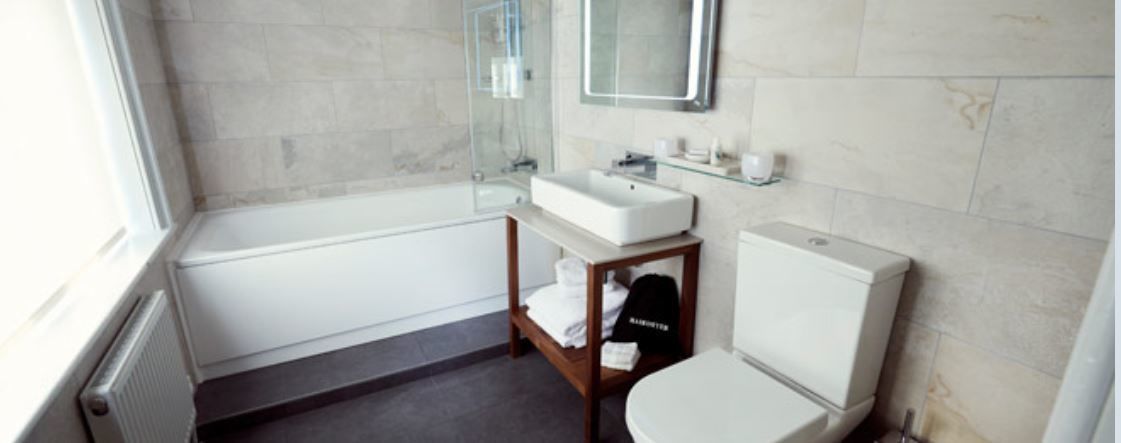 A bathroom with a bathtub, a sink, a toilet, and a mirror.