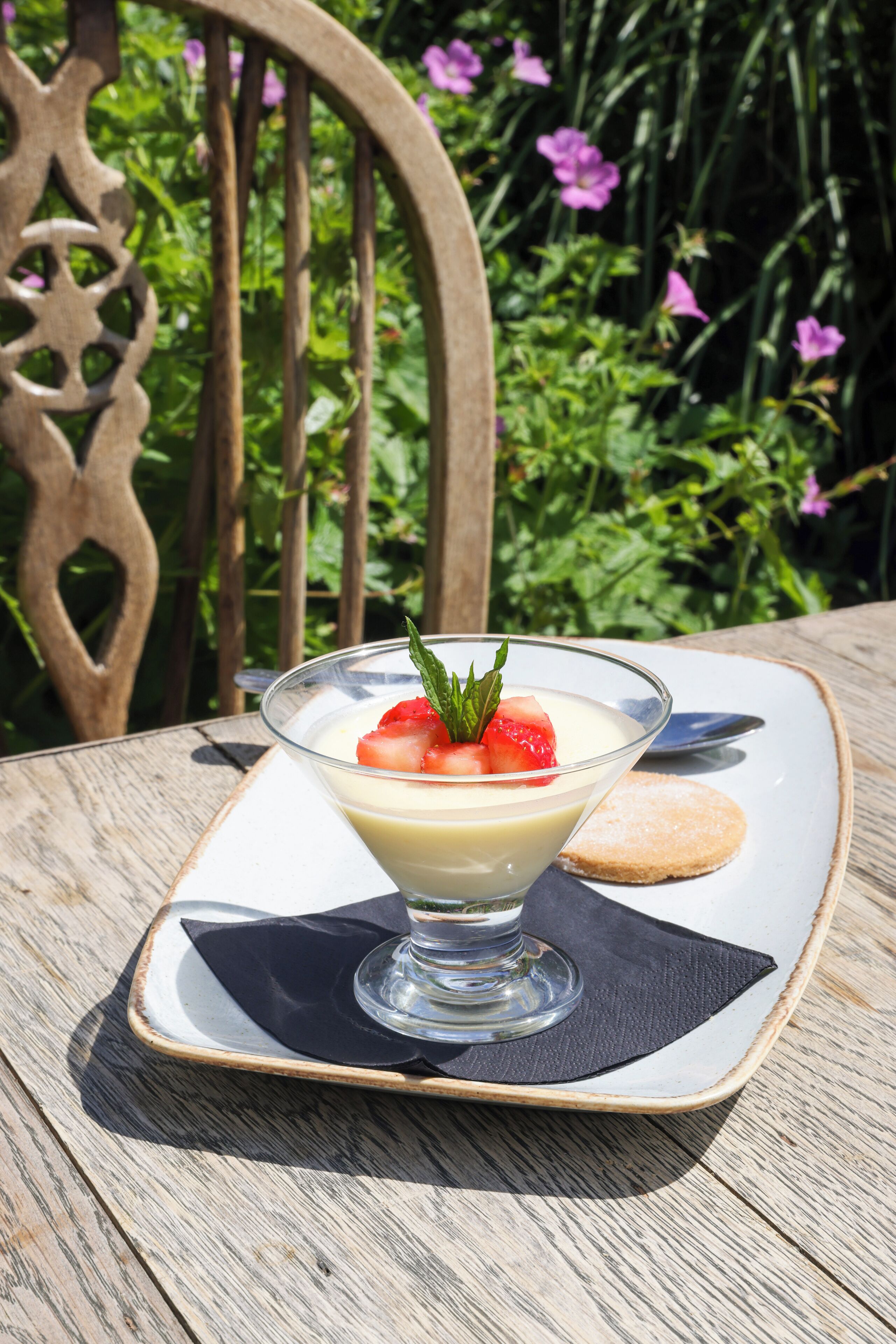 A dessert on a square plate with a black napkin underneath, placed on a wooden table.