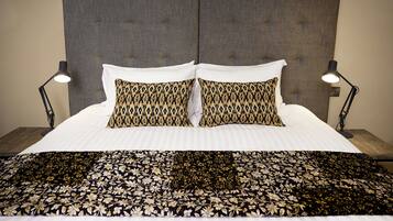A neatly made bed with a patterned pillow, a bedside lamp, and a floral bedspread.