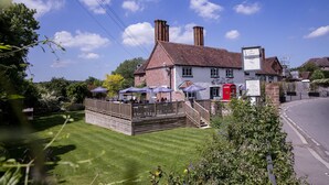 A traditional building with a brick facade, a wooden deck, and a red telephone booth. - The Tickled Trout (Maidstone)