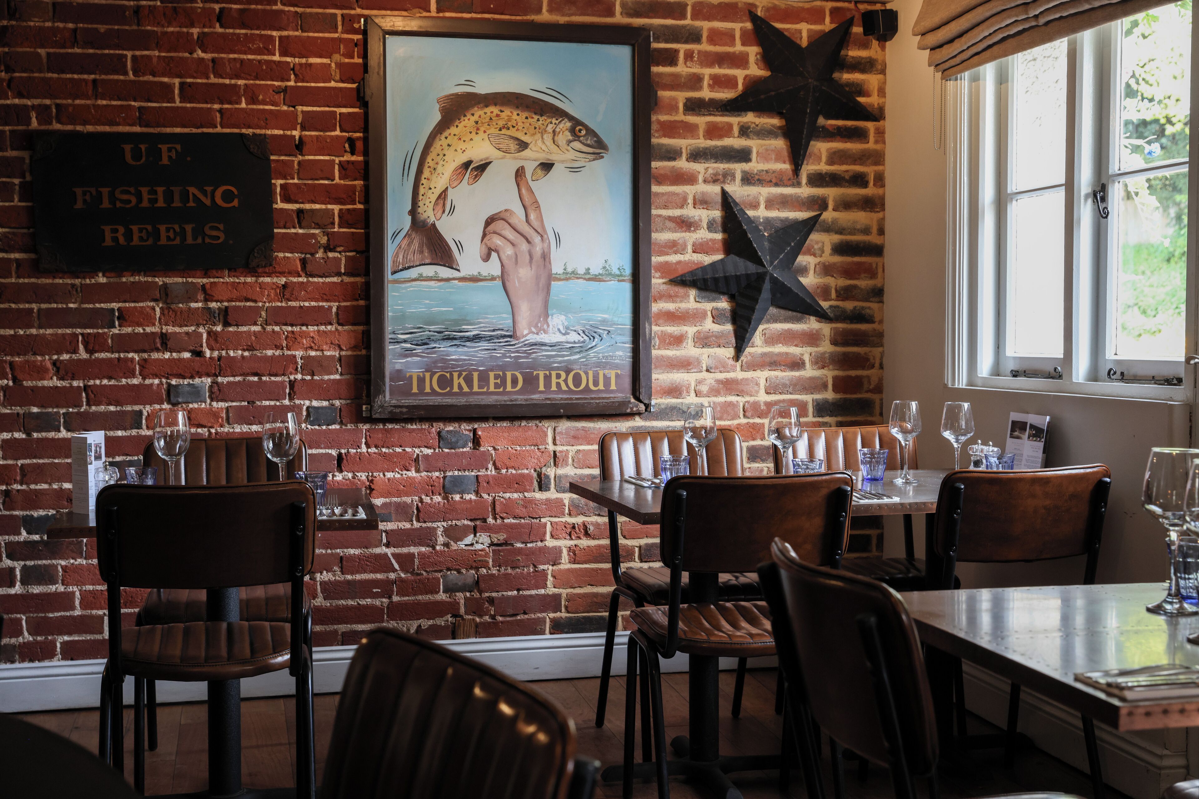 Un restaurant aux murs de briques, aux chaises et aux tables en bois, disposées pour le service.