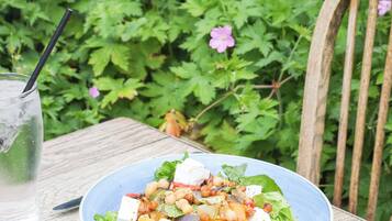 A table with a plate of salad, a glass of water, and a fork.