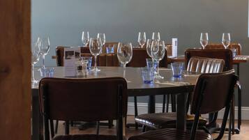 A dining area with a table set for a meal, chairs, a painting on the wall, and a ceiling light.