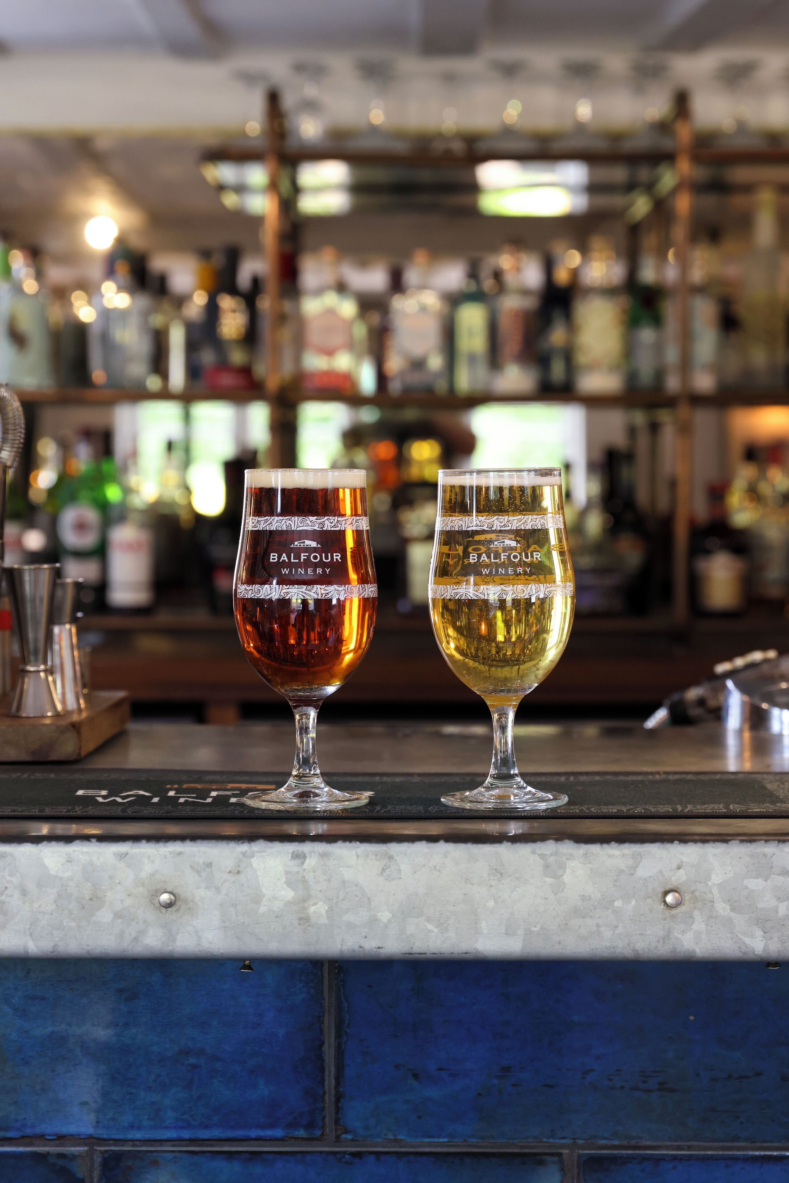 To ølglas på en bardisk med en uskarpt baggrund af hylder og flasker.