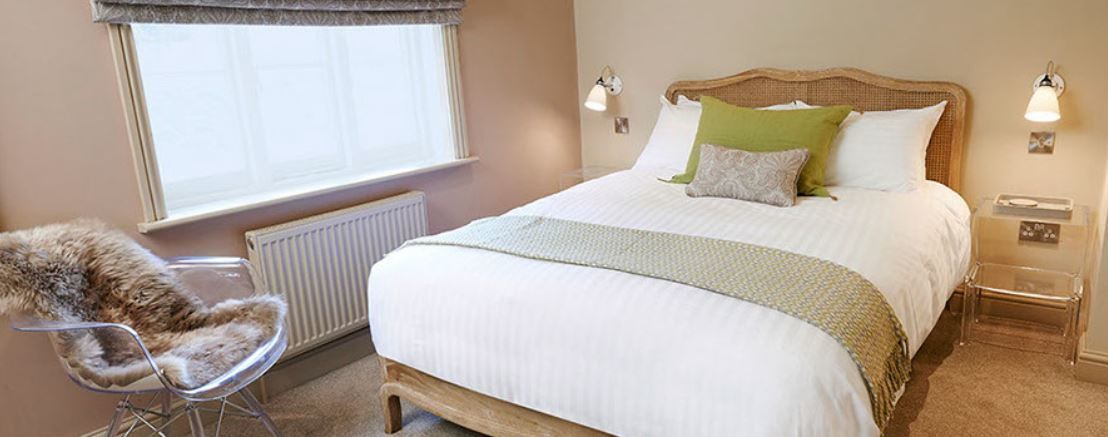A bedroom with a large bed, a chair, a window, and a nightstand.