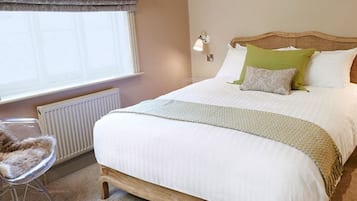 A bedroom with a large bed, a chair, a window, and a nightstand.