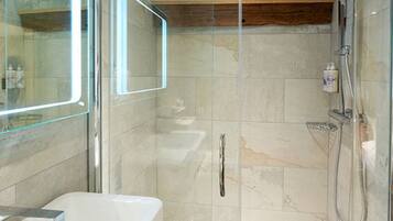 A modern bathroom with a glass-enclosed shower, a white bathtub, and a marble-tiled wall.