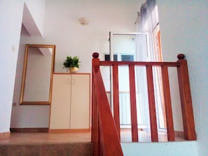 A staircase with a wooden handrail, a white door, and a potted plant on the wall. - Apartments Anto (Pula)