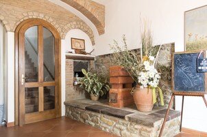 A stone fireplace with a wooden mantel, a wooden door with glass panels, and a chalkboard sign.