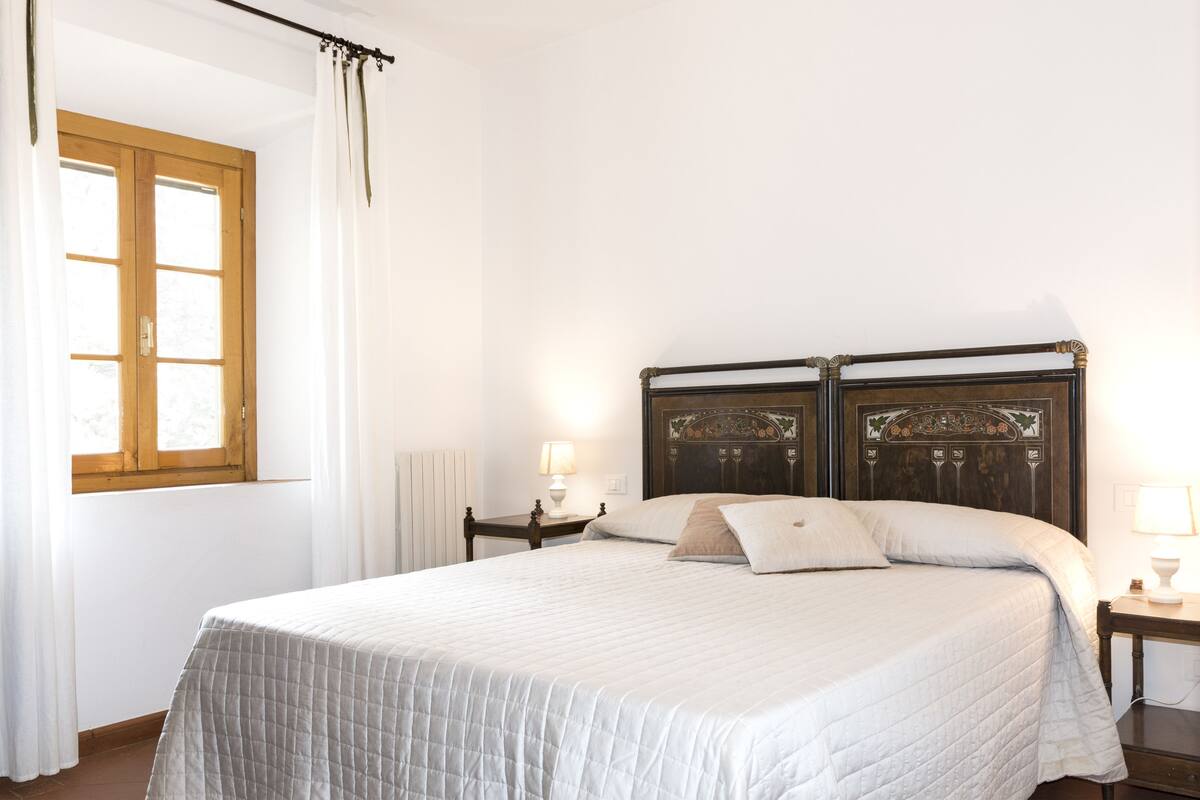 A neatly made bed with a quilted bedspread, a wooden headboard, and two bedside tables with lamps.
