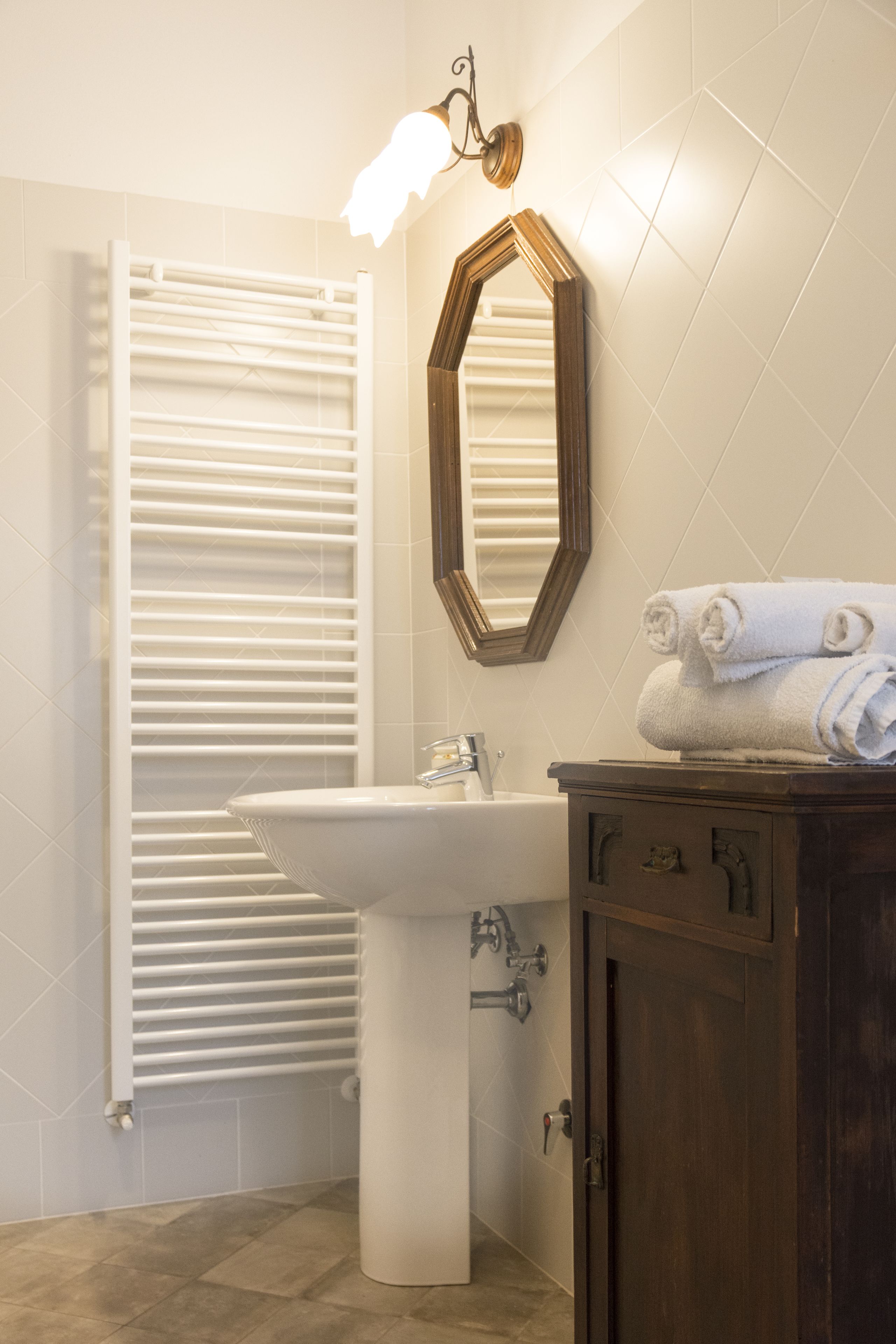 Une salle de bain avec un lavabo blanc, un meuble en bois, un porte-serviettes et un miroir au mur.