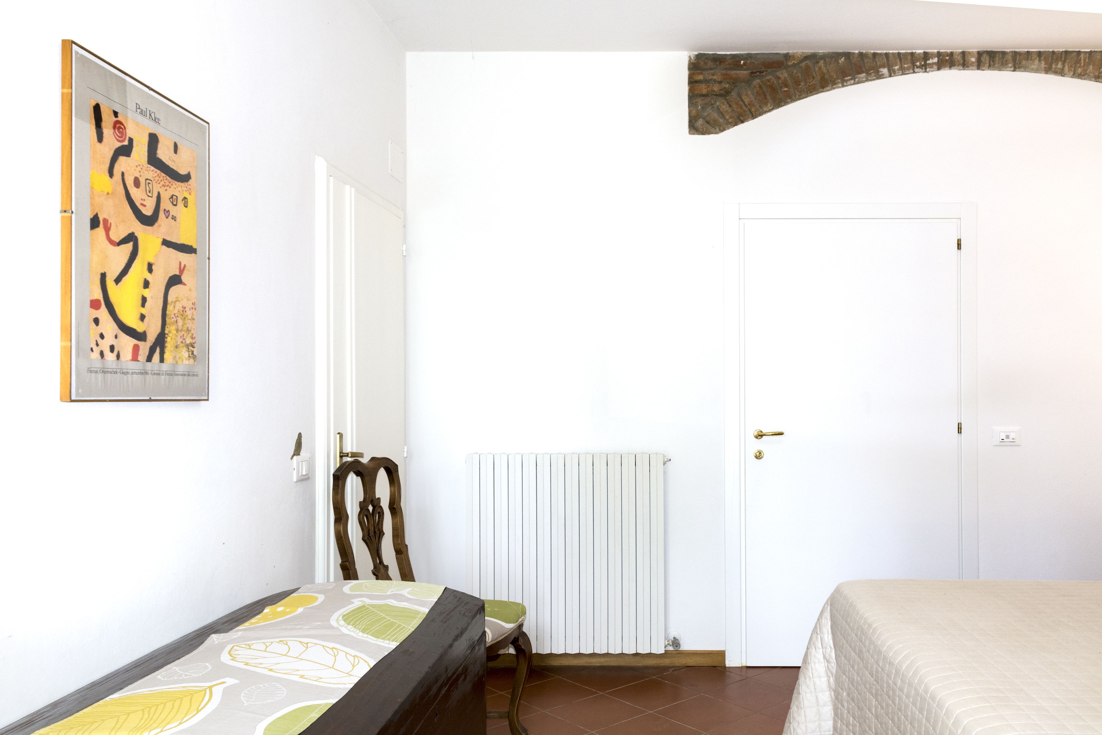 Une chambre à coucher avec un lit, une chaise, un radiateur et une porte.