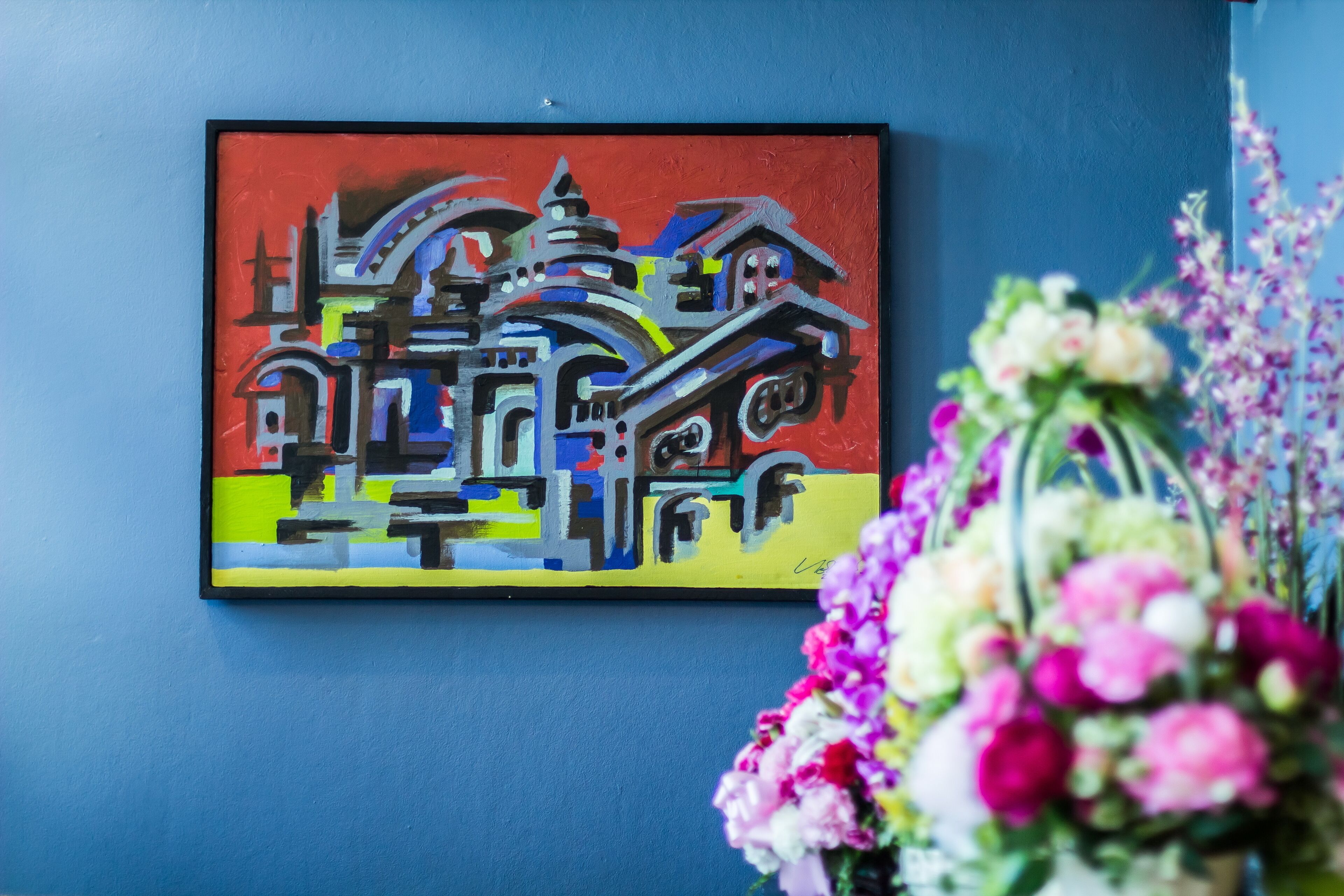 A colorful abstract painting on a blue wall.