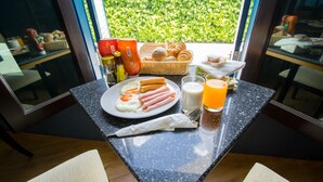 Een ontbijttafel met eieren, worst, brood en sap.