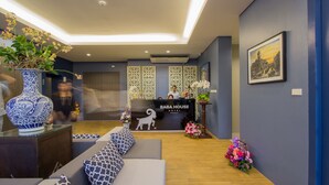 Een receptiegedeelte met een bank, een decoratieve vaas en een receptiebalie met de tekst 'Baba House Hotel'.