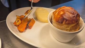 A plate with a baked pastry, a dollop of butter, and roasted vegetables.