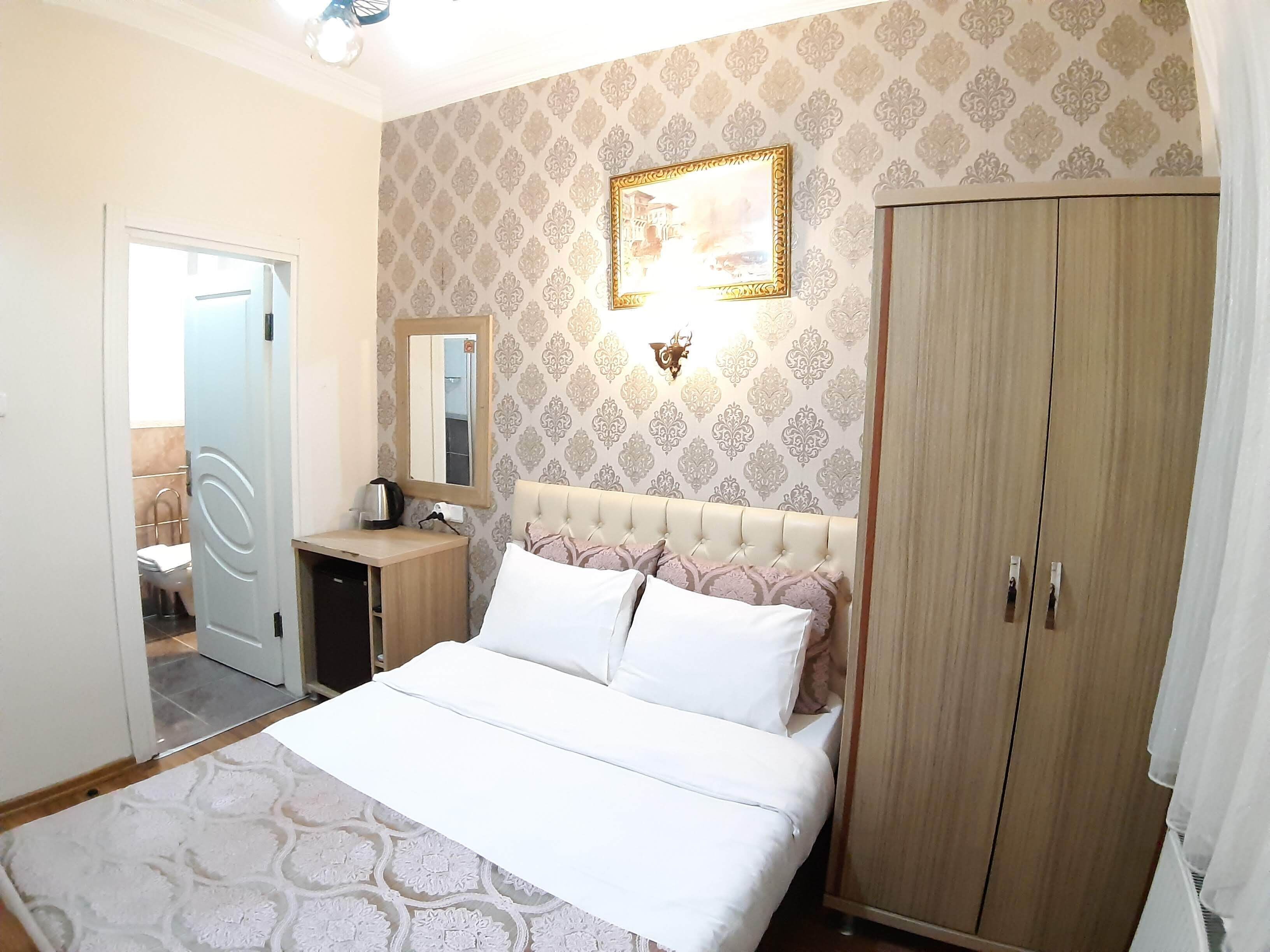 A bedroom with a bed, a wardrobe, a bedside table, a mirror, and a wall-mounted picture.