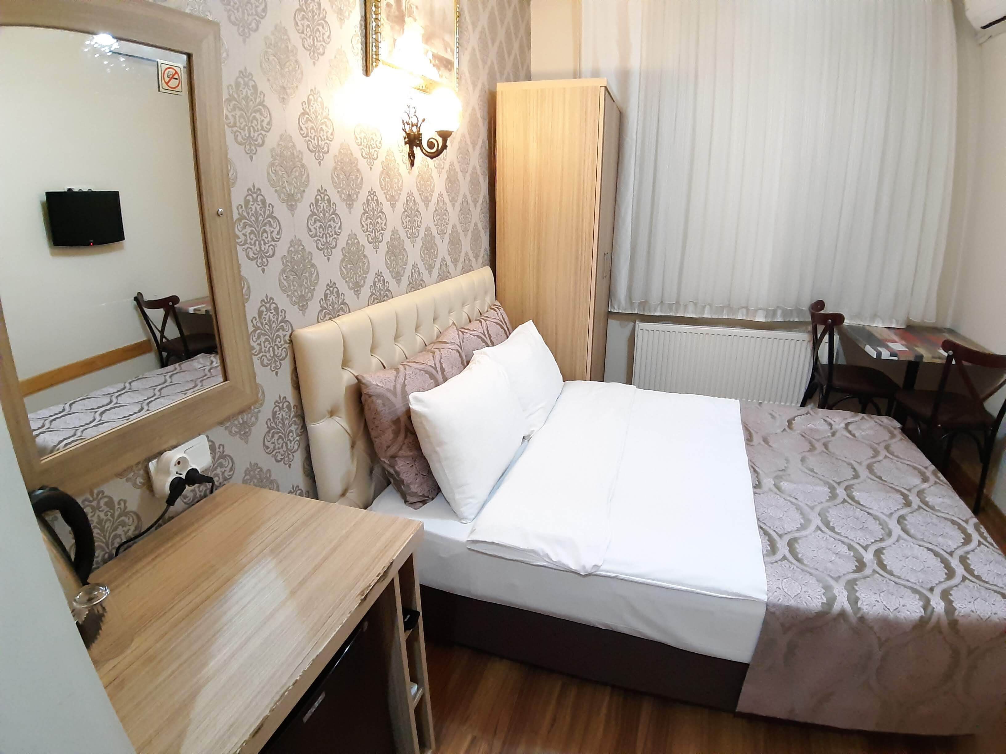 Una habitación de hotel con una cama, un escritorio de madera, un armario y un espejo.