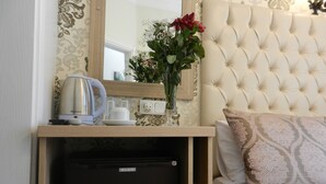 A neatly arranged hotel room with a bed, a bedside table with a kettle, a vase with flowers, and a small refrigerator. - Burak Apart Otel (Istanbul)