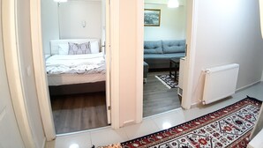 A hotel room with a bed, a sofa, a radiator, and a patterned rug. - Burak Apart Otel (Istanbul)