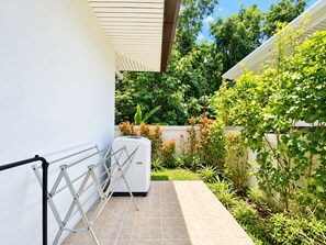 A residential outdoor area with a white wall, a metal drying rack, and a white appliance, possibly a washing machine, on a tiled patio. - Chalong 4BR Private Pool Villa | Near Big Buddha | Sleeps 10 (Tambon Chalong)