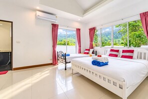 A hotel room with a large bed, two bedside tables, a window with a view of greenery, and an air conditioning unit. - Chalong 4BR Private Pool Villa | Near Big Buddha | Sleeps 10 (Tambon Chalong)