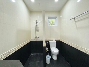 A bathroom with a shower, toilet, and a small window.