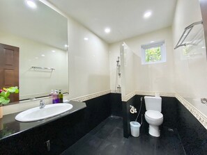 A modern bathroom with a large mirror, a sink, a toilet, and a shower.