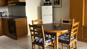 A kitchen with wooden cabinets, a dining table with chairs, a refrigerator, and a clock on the wall. - Private Apartment... (FREE WIFI ) (st pauls bay)