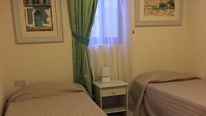 A room with two beds, a nightstand with a lamp, and two framed pictures on the walls. - Private Apartment... (FREE WIFI ) (st pauls bay)