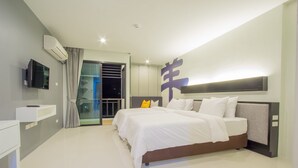 A modern bedroom with a large bed, a bedside table, a mounted TV, and a sliding glass door leading to a balcony. - A Nice clean superior king or twin room (Tambon Wichit)