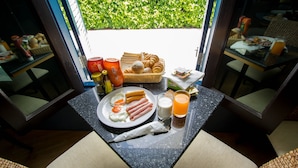 A breakfast table with croissants, eggs, and juice, set in a room with a view of greenery. - A Nice clean superior king or twin room (Tambon Wichit)