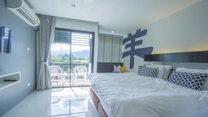 A hotel room with a large bed, a TV, a balcony with a view of the mountains, and a ceiling fan. - A Nice clean superior king or twin room (Tambon Wichit)