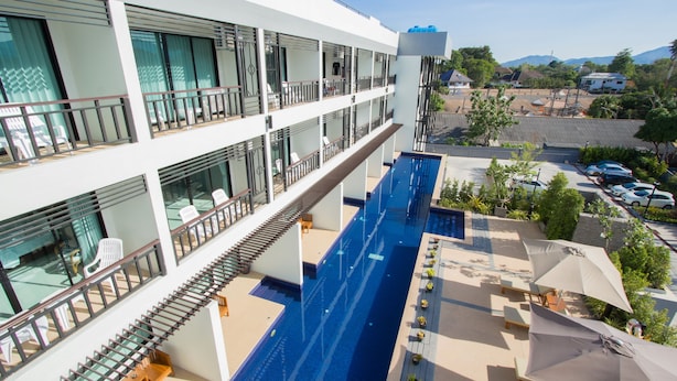 A multi-story hotel with a central swimming pool, outdoor seating, and a view of the surrounding area. - A Nice clean superior king or twin room (Tambon Wichit)
